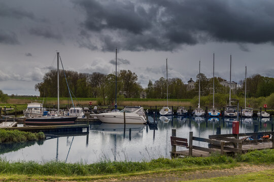Stormy sky over tranquil marina with sailboats and waterfront reflections. Itzehoe city. Germany.