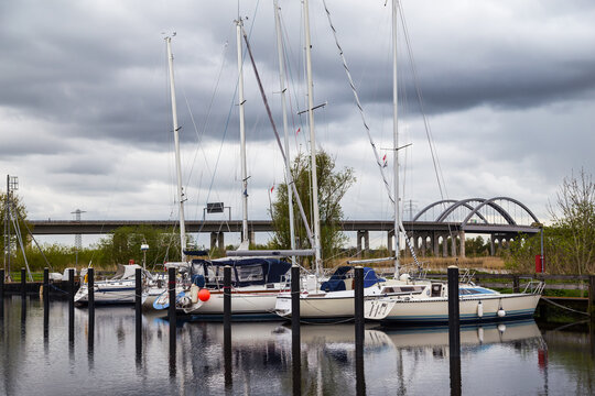 Stormy sky above a quiet marina with sailboats and reflections on the shore. In the background, a highway bridge over the St&ouml;r River. Itzehoe. Germany.