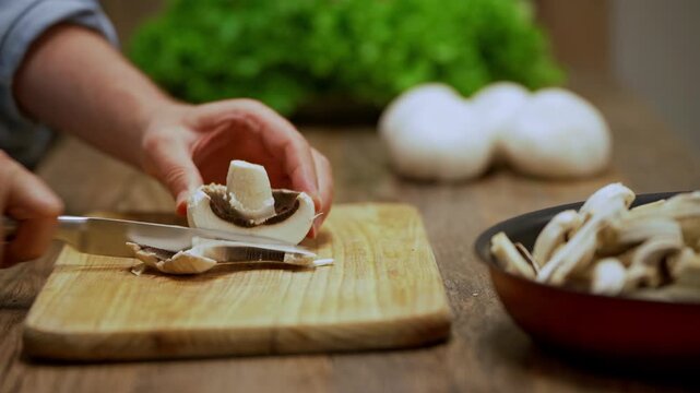 Chef slicing fresh champignon mushrooms on a wooden board, preparing healthy vegetarian ingredients for nutritious, wellness-focused recipes in a home kitchen.