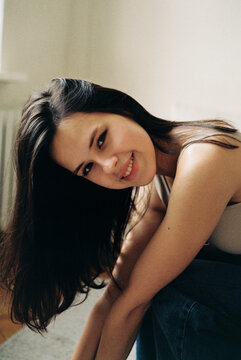 Smiling young woman leaning forward indoors  


