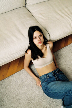 Woman lying on carpet by sofa in casual outfit  

