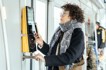 Passenger taps touch screen ticket machine inside tram, smart transit concept