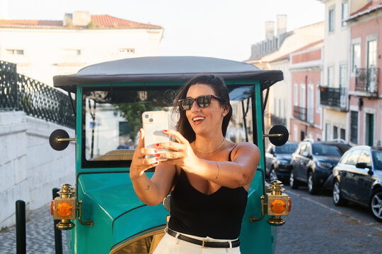 Woman Taking a Selfie in a Vibrant Vintage Car on a City Street