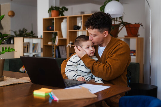 Young man works remotely alongside his son