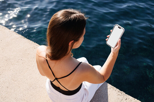 Person Holding Smartphone with White Screen by Water. Mockup