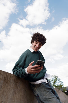 Young Man Enjoys Texting Outdoors on a Sunny Day
