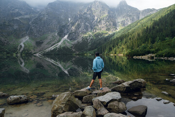 Man standing on rocks overlooking Morskie Oko lake in the Tatra Mountains © WellStock