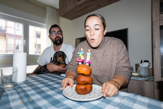Woman celebrating 31st birthday blowing candles with family
