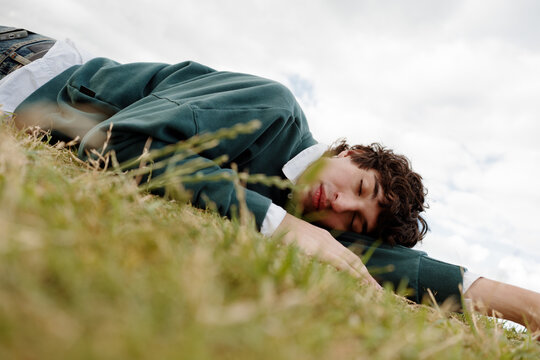 Young Man Resting on Grass Under Cloudy Sky During Day