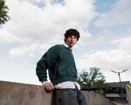 Young Man Posing Casually Outdoors With Cloudy Sky Backdrop