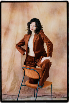 Woman on chair wearing rust velvet suit