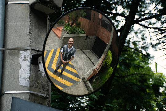 Man Smiling While being photographed in Round Mirror Outside