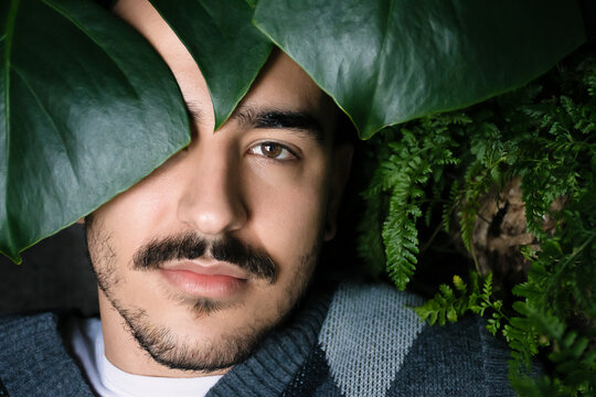 Portrait of a Young Man Surrounded by Lush Greenery Indoors