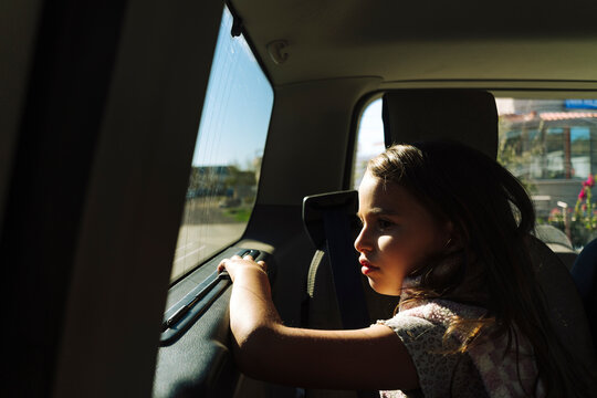 Little girl sitting in the backseat of the car, looking outside