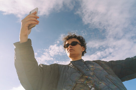 Casual woman using phone against blue sky with white clouds