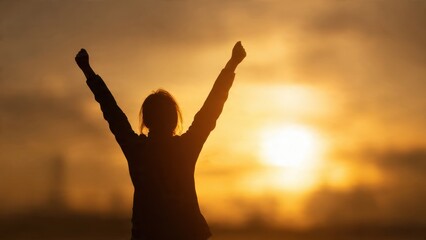 Fototapeta premium Silhouette of woman with arms raised at sunset
