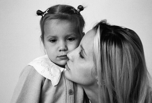 Black and white portrait of mother kissing daughter  

