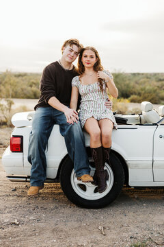 Young couple sitting on side of convertible 