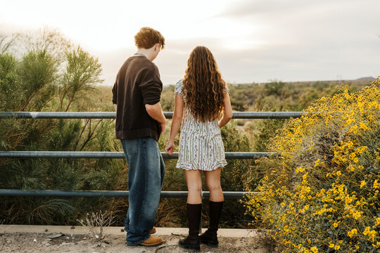 young couple looking over a fence into the desert