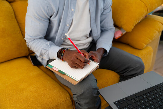 Man writing notes on sofa for remote work