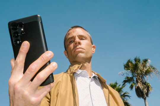 Modern Man Looking at Mobile Phone Screen Outdoors