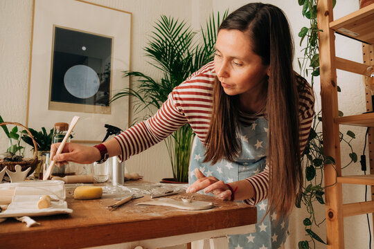 Woman working on pottery project in home studio with clay and to