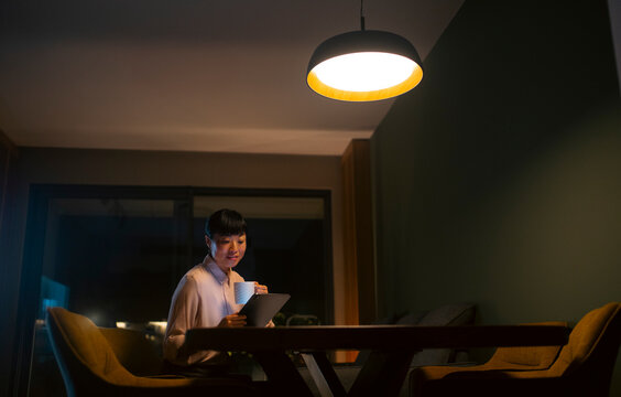 Asian woman working from home using tablet at night