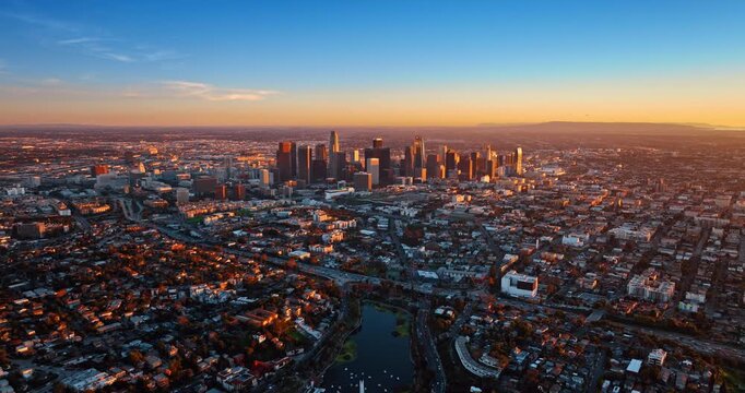 Vast panorama of Los Angeles, California, USA at sunset. Drone footage rising over the city scenery in the rays of setting sun.