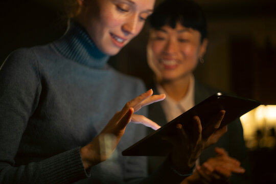 Business women collaborating on digital tablet at night