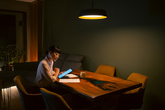 Woman working focused on tablet at home late at night