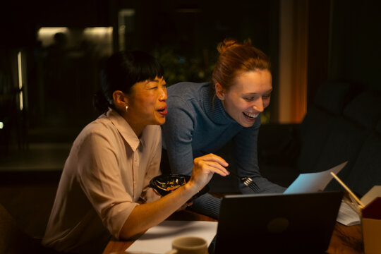 Diverse colleagues laughing while working late at office