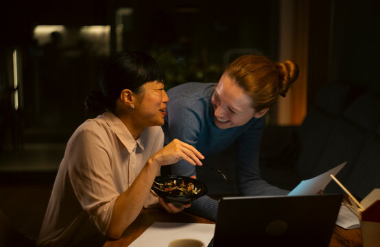 Colleagues smiling while working late and eating takeout
