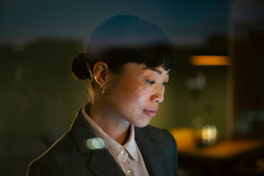 Asian businesswoman working late with digital screen reflection