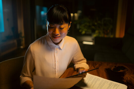 Woman working with tablet and documents late at night