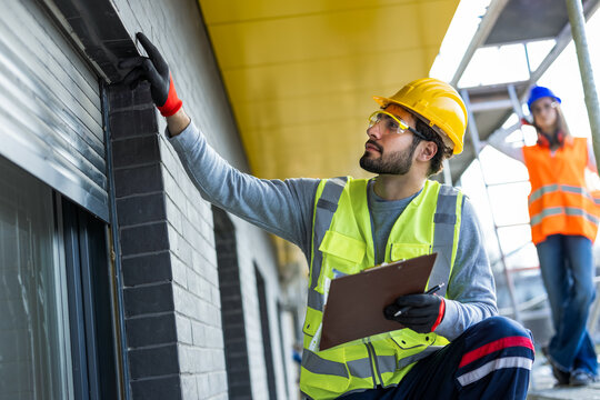 Professional engineers conducting a final quality inspection of window installation on a construction site.