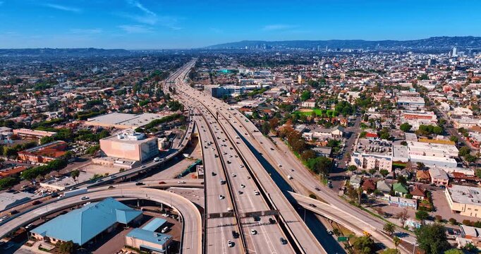 Footage over the highways and trestles of sunny Los Angeles, California, USA. Vast metropolis panorama with lots of greenery.