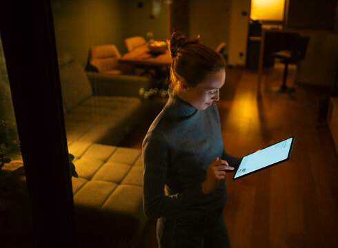 Woman using digital tablet at home during night