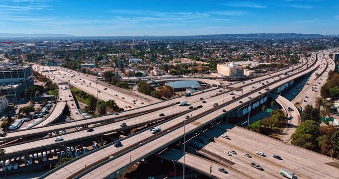 Cars run quickly by the highways and trestles at daytime. Verdant panorama of Los Angeles, California, USA from drone.