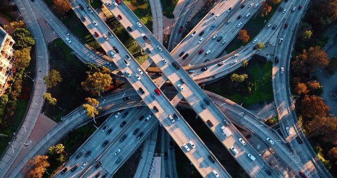 Transport moves by the highways of multi-level interchange. Top view on the intersection in Los Angeles, California, USA at sunset.
