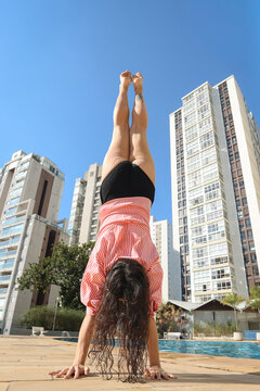 Handstand by the Pool With City Buildings