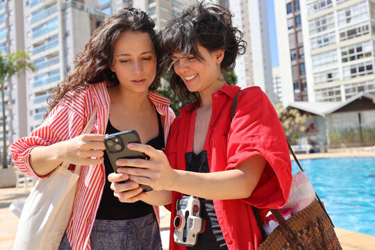 Friends using cell phone at pool