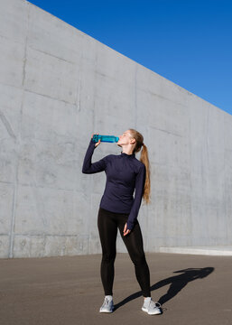 A woman drinks from a bottle after sports