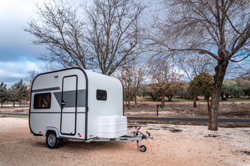 Compact camper trailer parked outdoors at a rustic campsite, offering adventure, freedom, and vacation during a road trip
