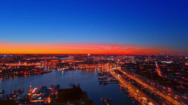 Beautifully lit cityscape of modern Stockholm, Sweden at night, Drone footage over the riverscape with numerous boats at the waterfronts.