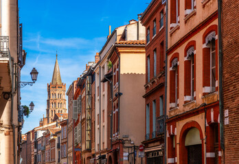 Fototapeta premium Rue du Taur in the historic center of Toulouse, and the bell tower of Saint Sernin in the background, in Haute Garonne, Occitanie, France.