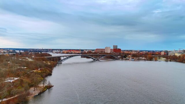 Approaching Vasterbron Bridge over the peaceful grey waterscape. Scenery of Stockholm, Sweden on a grey winter day. Aerial view.