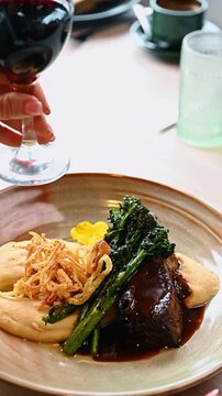 Braised beef short rib with mashed potatoes and broccolini. Slow cooked beef rib served with creamy puree fried onions and grilled broccolini on ceramic plate.