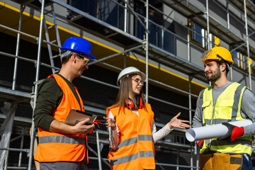 Group of construction specialists analyzing architectural project on a digital tablet at building...