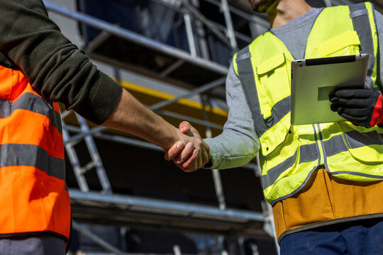 Close up of engineers shaking hands at construction site