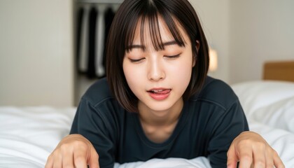 Fototapeta premium ベッドの上で舌を少し出し茶目っ気のある表情を見せる女性